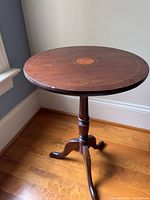 Full view of round dark brown tilt-top tripod side table
