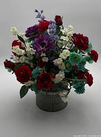 Front view of full artificial flower arrangement in metal bucket