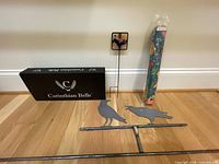 Overall lot showing boxed wind chime, glass stake, art pole, and metal bird stake