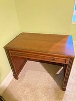 Front view of desk showing drawer and fluted leg detail