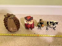 Four small decor pieces: pinecone pumpkin, straw owl, metal pilgrim bird, metal owl