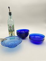 Group shot of four cobalt bowls, light blue menorah bowl, painted oil bottle with spout