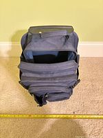 Top view of navy rolling backpack open, measuring tape for scale