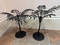 Front view of both black metal palm frond candle holders