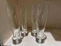 Four pilsner glasses grouped to show overall condition and style