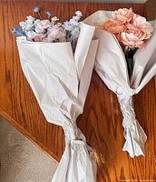 Two wrapped artificial flower bouquets on wood surface