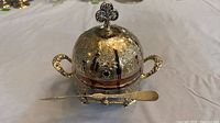 Front view showing domed butter dish, handles, glass liner edge, spreader on cradle