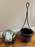 All items grouped: packaged hummingbird swing, packaged fruit feeder, wire hanging basket, metal plant stand with plastic pot