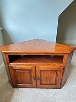 Front view of triangular oak veneer TV stand with open shelf and double cabinet doors