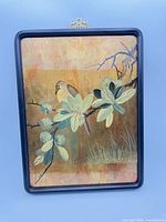 Front view of rectangular lacquered wood panel with bird and botanical painting, black frame, brass hanger