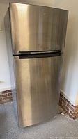 Front view of Whirlpool stainless steel refrigerator with top freezer door and handle