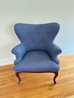 Front view of blue wingback chair showing upholstery and wooden legs
