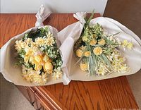 Both bouquets wrapped in paper on wooden surface