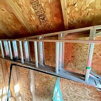 Full view of aluminum straight ladder hung horizontally inside shed
