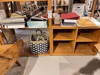 Shelving unit holding stacks of prints, multiple photo albums, and woven basket
