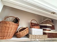 Shelf with multiple wicker baskets and stack of lidded storage boxes