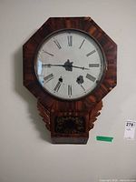Full view of wooden octagon wall clock on wall
