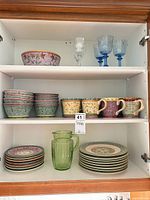 Cabinet shelves with entire dinnerware set, pitcher and stemware visible