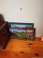 Group of five framed artworks leaning against wall