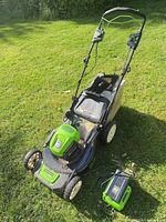 Full view of mower with battery installed and charger on ground