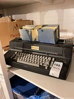 Front view of IBM electronic typewriter on shelf, box on top