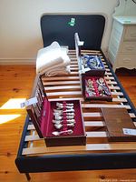 Twin upholstered bed frame with wood slats, metal legs and white bedspread folded at head end