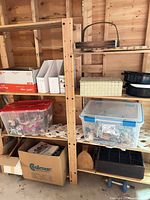 Wood shelving with plastic totes of dolls, wooden box, magazine file holders, black pans, seedling tray