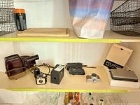 Shelf view showing cameras, slide projector, Polaroid box and accessories