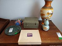 Group shot showing vase, rice wine bottle, plaque, mask, fabric box and additional flat box