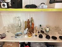 Overall view showing pitchers, figurines, cloisonné pieces, prayer wheel, small glassware