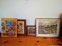 All four framed artworks standing against wall