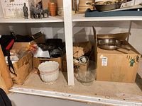 Shelf with boxes containing baking pans, muffin tins, planter, glass bowl, utensils