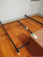 Full view of assembled black metal queen bed frame on wood floor