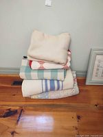 Stack of five blankets and quilts on wood floor