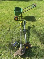 Overall view of lawn spreader, string trimmer, charger and battery