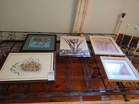 Five framed prints laid on box-spring for full lot overview