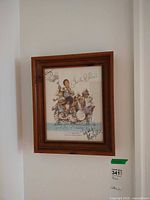 Full view of framed signed illustration print hanging on wall