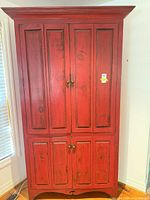 Front view of red armoire showing four paneled doors and hardware