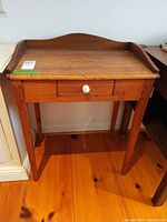 front view of solid wood desk showing gallery back, drawer and legs