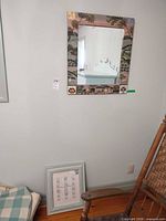 Mirror hanging on wall above chair and small picture frame on floor