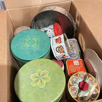 Assorted tins, colander and stoneware jar inside box