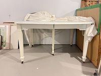 Full view of table showing drop-leaf design, legs and casters