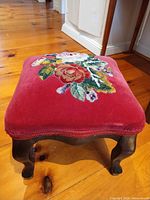Full view of footstool showing velvet seat with floral needlepoint and wooden cabriole legs