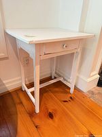 Full view of white distressed wooden side table against wall