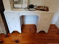 Front view of white painted four-drawer wood desk with fluted trim and bracket feet