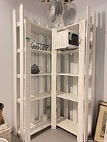 Full view of white wooden corner shelving unit with five shelves each side