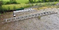 Two groups of aluminum ladder sections laid out on gravel