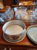 Overall lot showing springform pan, fluted pan, glass baking dishes, frosted bowl, jars in rack