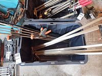 Totes containing multiple long bar clamps with orange pads and silver bars