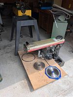 Radial arm saw detached from metal stand with cord and two blades visible